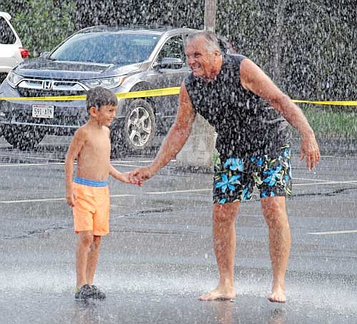 Five-year-old Teiago Miralda and Mike Heppe take a turn getting sprayed by water from the Woodruff Fire Department’s ladder truck in the parking lot of the Holy Family Catholic Church on Saturday, July 8, in Woodruff. The “Splash Party” is a fundraiser to benefit Frederick Place in Rhinelander, an emergency, temporary shelter for families, women and men who are experiencing homelessness. (Photo by Brian Jopek/Lakeland Times)