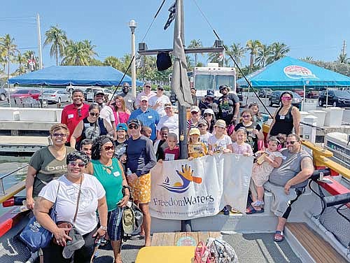 Participants and volunteers of a past Freedom Waters Foundation boat outing in Florida pose for a picture on the water. (Contributed photograph)