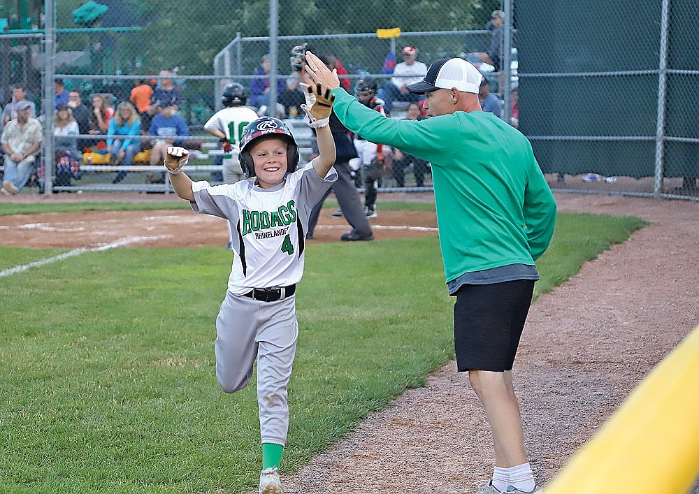 Rhinelander’s Jeter Vander Gailen high-fives coach Jeremy Vander Gailen after scoring a run during the fifth inning of a Little League District 5 10U tournament game against Wausau American in Rib Mountain Tuesday, July 18. (Bob Mainhardt for the River News)
