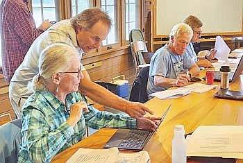 Susan Holloway of Little Tamarack Lake and Jim Kreitlow (standing) look at lake data at the Lake Toolkit Workshop. George Lannert and Doug Pinney from Plum Lake attended the workshop as well to learn more about how to use lake data in management strategies on their own lake. (Contributed photograph)