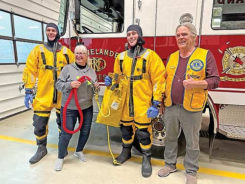 Rhinelander firefighters Scott Rozmarynoski, left, and Tanner Perry, center, model the department’s new rescue suits for Linda Campbell of the Seventh Day Adventist Thrift Shop and Bob Berns of the Rhinelander Lions Club on Tuesday, Oct. 23, 2023. The Lions Club, of which Campbell is also a member, and the thrift shop teamed up to purchase the new rescue suits for the department. (Photo by Heather Schaefer/River News)
