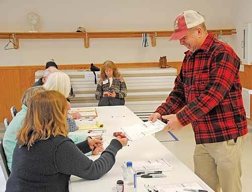 John MacLean, one of the candidates for Presque Isle town chair in the court ordered special election on Nov. 14, receives a ballot from poll worker Cathleen Eugster. MacLean retained his seat on the town board per the Nov. 14 results — 294 to 265. (Photo by Brian Jopek/Lakeland Times)