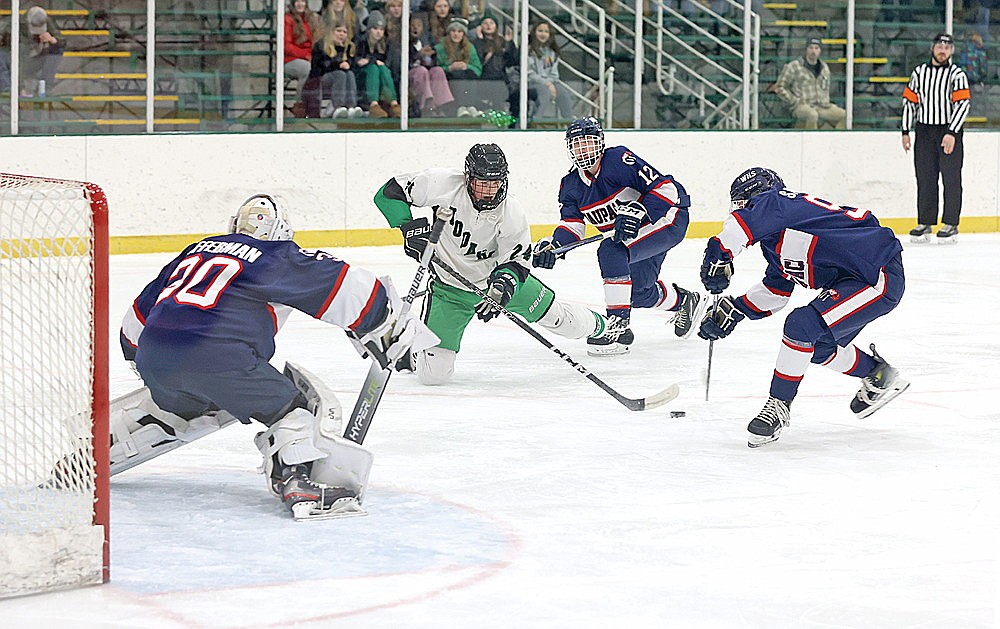 Rhinelander’s Zach Edyvean attempts a shot between Waupaca defenders Cullen Frierdich (12) and Parker Saunders (91) during the first period of a GNC boys’ hockey game at the Rhinelander Ice Arena Friday, Dec. 8. Edyvean scored a third period power play goal for Rhinelander, but the Hodags fell to the Comets, 7-2. (Bob Mainhardt for the River News)
