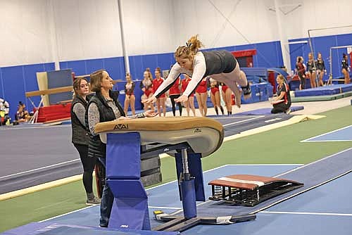 Vicky Wiza lifts off onto the vault with coach Laura Hayes assisting and coach Kaitlin Miesbauer in the background during the Snowflake Invite Saturday, Dec. 9 at YMCA of the Northwoods in Rhinelander. (Photo by Bob Mainhardt for the River News)
