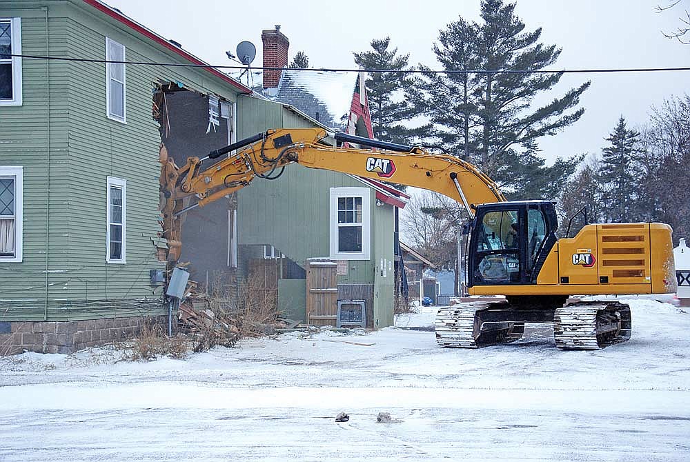 John Hogan with Schrom’s Excavating uses a company excavator to begin the demolition Monday of the Coach House Apartments in downtown Minocqua. Since heavy damage in a fire in January of this year, repair and renovation estimates made it cost-prohibitive to save. That and concerns regarding public safety prompted the demolition. (Photo by Brian Jopek/Lakeland Times)