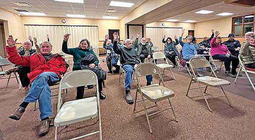 Boulder Junction residents attending a public hearing raise their hands in favor of the town pursuing a shared emergency medical service district with Manitowish Waters, Presque Isle and Winchester on Wednesday, Dec. 20. (Photo by Trevor Greene/Lakeland Times)