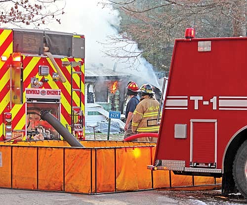 Firefighters with the towns of Newbold, Pine Lake and Lake Tomahawk work to extinguish a structure fire on South Ranch Road on Thursday, Dec. 14, in Newbold. Ryan Lee Bennett, 30, of Rhinelander, was charged in connection with the fire. (Photo by Trevor Greene/Lakeland Times)