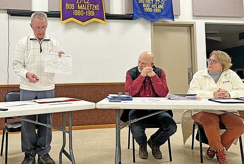 Town chairman John Hanson displays town lake maps he gathered for the discussion of hazardous wakes while town supervisors, Lynn Schroeder, center, and Joan Farrell look on during town board meeting Tuesday, Jan. 9, in Manitowish Waters. (Photo by Trevor Greene/Lakeland Times)