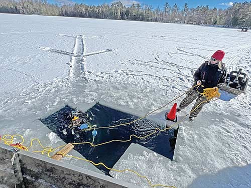 Laura Fuhrman, a civilian member of the Oneida County dive team since 2008, tends the line for Dan Jesse, also a civilian member of the dive team since 2008, during a training on Clear Lake Sunday, Feb. 18, in Woodruff. (Photo by Kate Reichl/Lakeland Times)