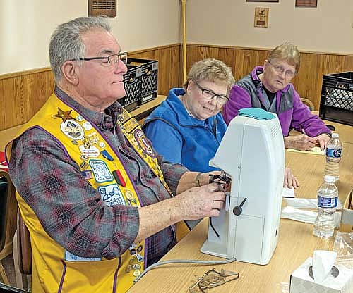 Lion Dennis Hirtz uses the lensometer to determine the eyeglass prescription while Lions Mary Ellen Mazurczak and Jan Heeren watch. (Contributed photograph)