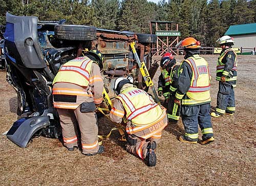 Minocqua fire chief Rich Carani (kneeling) is among other firefighters working to dismantle a vehicle stabilization system at the end of a block of training in vehicle extrication on Saturday, Feb. 24, in Arbor Vitae. (Photo by Brian Jopek/Lakeland Times)