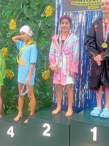 Morgan Massey celebrates her second-place finish on the podium in the 25-yard backstroke at the 10 & Unders state meet Feb. 24-25 in Ashwaubenon. (Contributed photograph)