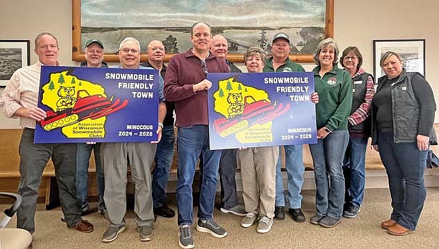 The town of Minocqua was presented from the Association of Wisconsin Snowmobile Clubs (AWSC) signs declaring it as a Snowmobile Friendly Town 2024-28 on Tuesday, April 16. Pictured, from left, are Minocqua Forest Riders Snowmobile Club (MFRSC) member Tom Teichmiller, MFRSC member John Ryan, MFRSC member Curt Christensen, MFRSC member Dan Sikora, town chairman Mark Hartzheim, Dan Solheid, AWSC president Lori Heideman, MFRSC president Jerry Wakefield, MFRSC member Eileen Ryan, Let’s Minocqua Visitors Bureau managing director Barb Wagoner and Let’s Minocqua Visitors Bureau community manager Kailey Barutha. (Photo by Trevor Greene/Lakeland Times)