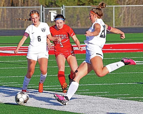 Taylor Heleniak (6) and Medford’s Talyn Peterson run to the ball as Josie Wentland kicks it away in the second half Thursday, April 25 at Raider Field in Medford. Heleniak scored the game-winning goal in the first half with the assist to Wentland. (Photo by Matt Ffrey/Star News)