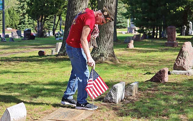 Steve Shaker places American flags at veterans graves on Sunday, May 19, at Evergreen Cemetery in Woodruff. (Photo by Kate Reichl/lakeland times)