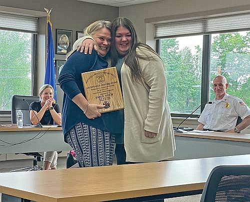 Minocqua town supervisor Erika Petersen, seated left, and Minocqua fire chief Rich Carani watch as Pam Carroll, standing left, is embraced while presenting police dispatcher Emily Koch an Exceptional Service Award during the Minocqua town board meeting on June 4. (Photo by Brian Jopek/Lakeland Times)