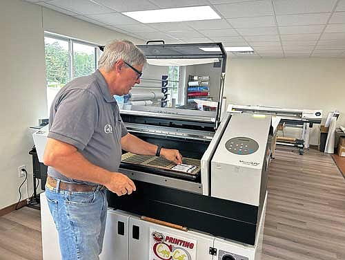 Rick Engels, owner of Copy Cat Printing, lines up pens in one of their newest printing machines on Friday, June 7, in Minocqua. (Photo by Mikey Rottier/Lakeland Times)