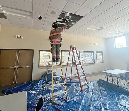 Minocqua firefighter Casey Cox uses a thermal imaging camera to check for hot spots following a light fixture fire in the program room of the Minocqua public library on Tuesday, June 25. (Contributed photograph)