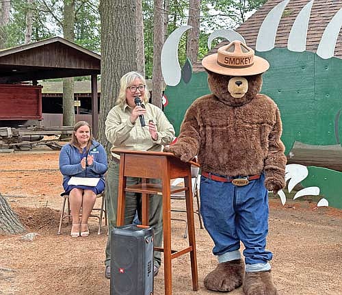 Rhinelander Area Chamber of Commerce CEO Lauren Sackett, left, applauds as Veronica Hinke, public affairs officer for the Chequamegon Nicolet National Forest, wishes Smokey Bear a happy birthday during a reception at the Pioneer Park Historical Complex in Rhinelander Wednesday, July 2, 2024. (Photo by Heather Schaefer/River News)