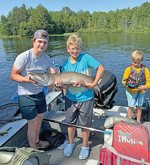 Isaac Niemeyer, 12, of Lombardo Ill. shows off his big catch with the help of a local fisherman, Jaden (last name unknown), left, on Saturday, July 6, on Lake Tomahawk. (Contributed photograph)