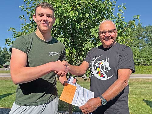 Tyson Skubal, left, is officially awarded a bear tag he won through a Northwoods Youth Deer Hunt Challenge drawing and donated by Vern Schaller, right, on Thursday, July 25, in Minocqua. (Photo by Trevor Greene/Lakeland Times)