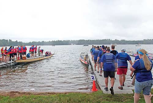 Members of two dragon boat racing teams made up of Trig’s co-workers and family members,”Fiery Fresh,” left, and the “Sea Merchants,” board their dragon boats before their “Grocery Wars” exhibition race during the Minocqua Dragon Boat Festival on Saturday, Aug. 17. The Sea Merchants won the race. (Photo by Brian Jopek/Lakeland Times)