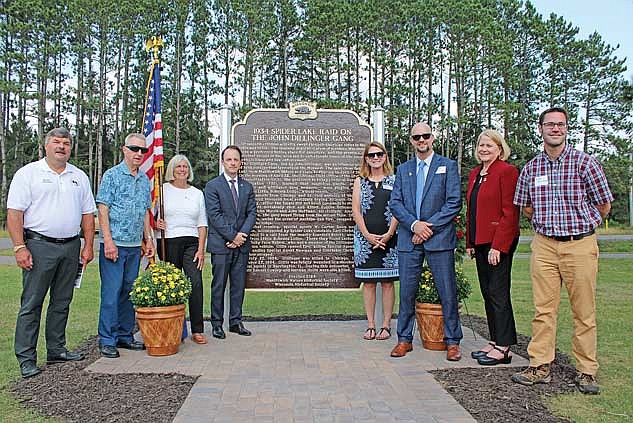 A new Wisconsin Historical Marker was unveiled near the intersection of U.S. Highway 51 and Airport Road on Saturday, Aug. 24, in Manitowish Waters. The marker honors those impacted by the Dillinger Gang in 1934. Those present for the unveiling and dedication ceremony are, from left, state representative Rob Swearingen, Manitowish Waters town chairman John Hanson, Manitowish Waters Historical Society board member Kay Krans, FBI Milwaukee Special Agent in Charge Michael E. Hensle, state senator Mary Felzkowski, FBI special agent Scott Mahloch, executive director of the Society of Former Special Agents of the FBI Nancy Savage and Wisconsin Historical Society program coordinator Fritzi Heimdahl. (Photo by Trevor Greene/Lakeland Times)