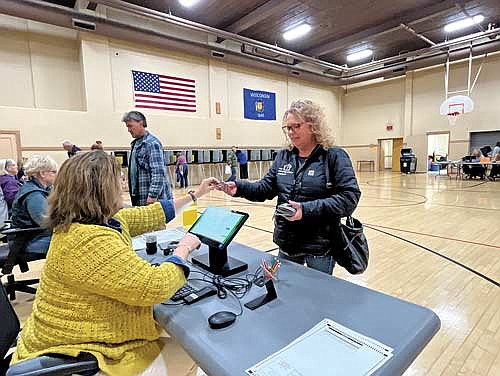 Minocqua town clerk Roben Haggart hands voter Kelli Gray her driver’s license during the process to register Gray to vote during election day in Minocqua on Tuesday, Nov. 5. (Photo by Trevor Greene/Lakeland Times)
