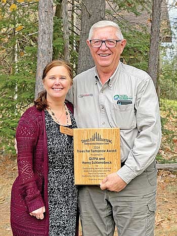 Trees For Tomorrow executive director Cheryl Todea, left, presents the Trees For Tomorrow Award to Henry Schienebeck and Great Lakes Timber Professionals, honoring his exceptional commitment to natural resources education and support for sustainable forestry practices. (Contributed photograph)