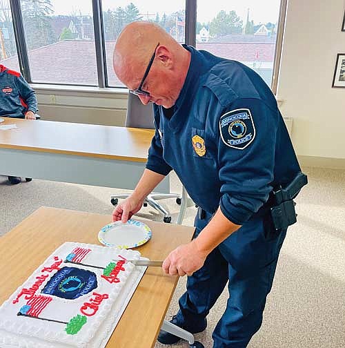 Retiring Minocqua police chief Dave Jaeger cuts the cake served in his honor during a “retirement gathering” hosted by the town of Minocqua on Wednesday, Nov. 13. (Photo by Brian Jopek/Lakeland Times)