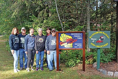 Members of the Manitowish Waters Sno-Skeeters Snowmobile Club and Manitowish Waters Visitors Bureau director Lynsey Burzinski with the new sign designating Manitowish Waters as a “Snowmobile Friendly Town” on Saturday, Sept. 21. From left, Leigh Ann Petrusky, Tom Petrusky, Burzinski, Chris Troller, Kim Yencich and Dave Everdon. (Photo by Kate Reichl/Lakeland Times)