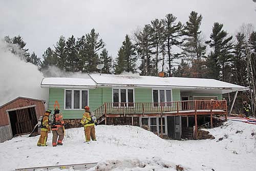 The subject of the Dec. 14 practice burn on Mercer Lake Road
has smoke rolling from its roof as the first iteration of firefighters
extinguish flames inside the structure. (Photo by Brian Jopek/Lakeland Times)