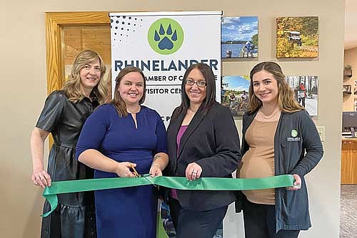 Staff members of the Rhinelander Area Chamber of Commerce, from left to right Katie Younker, Lauren Sackett, Rachel Boehlen and Angela Badeau, pose to cut a ceremonial ribbon honoring the chamber’s 100th anniversary and renovations to the chamber office Tuesday, Dec. 17. (Photo courtesy of Rhinelander Area Chamber of Commerce)