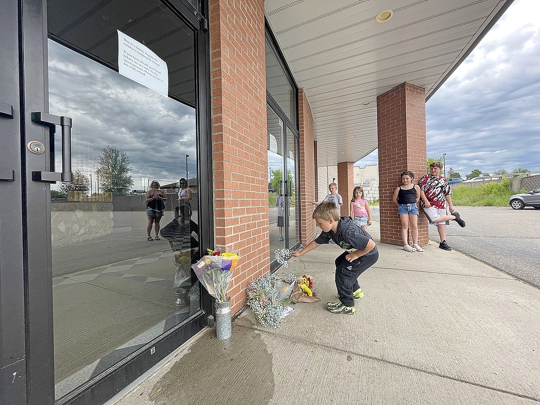 In this June 12, 2024 file photo, Jentry Alsteen, 5, places flowers at the entrance of Rouman Cinema in Rhinelander in memory of Rouman Amusement Company president George Rouman. Rouman was killed in a two-vehicle crash on U.S. Highway 51 south of Tomahawk, on Sunday, June 9. Rouman’s passing, along with the loss of fellow community leaders Dan Bauer and Tom Kelly has been selected as our top local news story of 2024. (Photo by Jeremy Mayo/River News)