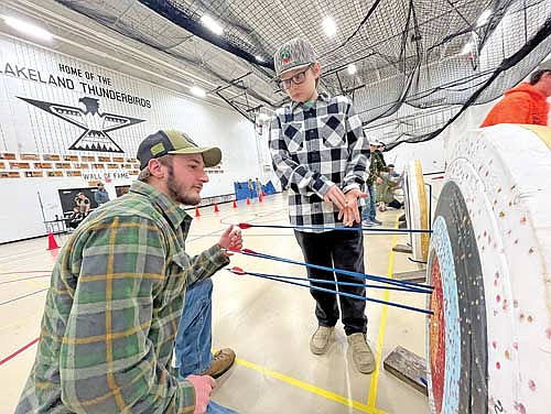 Logan Strasburg helps youth hunter Levi Keckeisen, 10, pull his arrows during the bow shooting contest during the Northwoods Deer Hunt Challenge banquet at Lakeland Union High School in Minocqua Wednesday, Jan. 1.
(Photo by Trevor Greene/Lakeland Times)