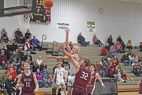 Brooks Lenz connects on a floater against the defense of Antigo’s Luke Bastle (32) in the second half of a conference game Friday, Jan. 31 at Ted Voigt Court in Minocqua. Lenz scored a career-high 14 points. (Photo by Brett LaBore/Lakeland Times)