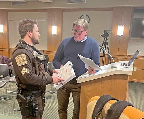 During the Feb. 20 meeting of the Oneida County Board of Adjustment, Sgt. Brian Keller with the Oneida County Sheriff’s Office serves Kirk Bangstad with notice of an invasion of privacy lawsuit against him filed by Lakeland Times publisher Gregg Walker and the newspaper’s general manager, Heather Holmes. (Photo by Brian Jopek/Lakeland Times)