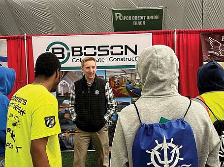 Nick Anderson, project manager with The Boson Company Inc., talks to a group of young men checking out his company’s booth. (Photo by Trevor Greene/Lakeland Times)