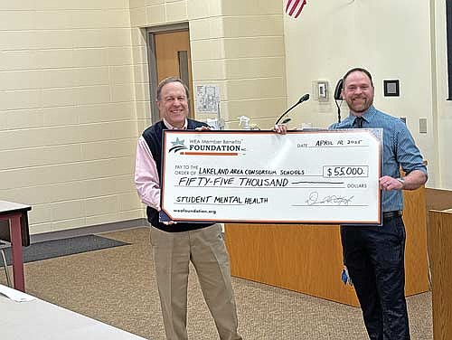 Adam Nowak, Project AWARE mental health coordinator for the Lakeland area consortium school districts, accepts a $55,000 check from Steve Goldberg, executive director of the WEA Member Benefits Foundation which is the organization that awarded the grant. (Photo by Trevor Greene/Lakeland Times)