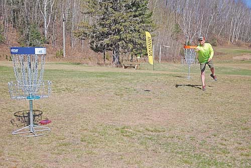 Devin Hamus of Neenah, in the Lakeland area for the weekend visiting family as well as participating in the Spring Fling flex disc golf tournament at Minocqua Winter Park, makes a warm-up disc toss at a basket before setting out on the course on Saturday, May 10. (Photo by Brian Jopek/Lakeland Times)