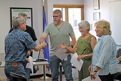 Board member Merlin Van Buren, left, shakes hands with new board member Kurt Helke, joined by re-elected board members Ron Lueneburg (obscured), Judy Conlin and Mary Peterson, after presiding over the oath-taking ceremony. (Photo by Michael Strasburg/Lakeland Times)