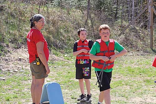 YMCA staff instructs Drayvin Buelow (left) and Lucas Knoeck on how to appropriately adjust and fit a life jacket at the aquatics station at the Recreational Rodeo on May 9. (Photo by Michael Strasburg/Lakeland Times)