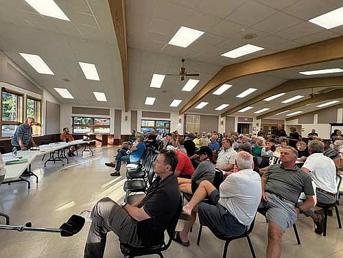 Town supervisor Lynn Schroeder holds a microphone as resident Carla Hameister offers input to the town board during a public hearing on a proposed enhanced wake ordinance on Tuesday, May 13, in Manitowish Waters. (Photo by Trevor Greene/Lakeland Times)