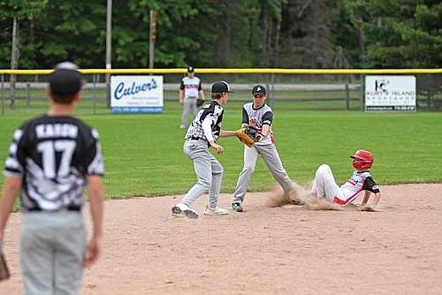 Parker Ecklund, left, and Sean Sass look to get an out as Roman Piorkowski slides in safely at second base in the second inning of a baseball game Wednesday, June 18 at the Minocqua Park Complex. (Photo by Brett LaBore/Lakeland Times)