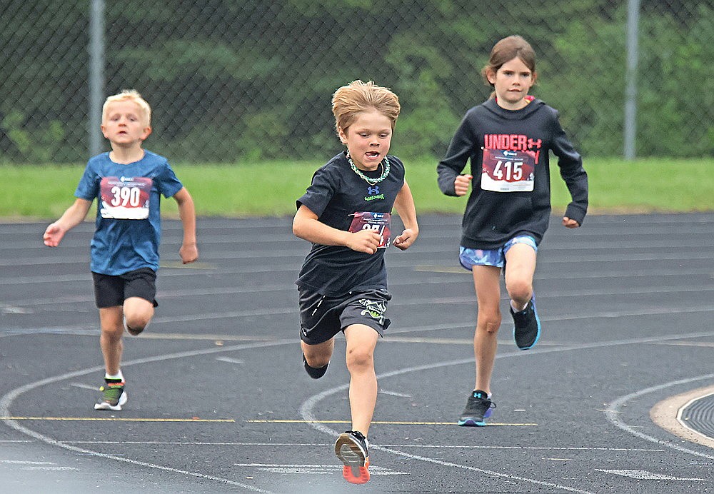 Rhett DeVault, center, of Rhinelander, Will Eastwood (390) of Tomahawk and Kara Koch (415) of Three Lakes compete in the 200-meter dash during a Northwoods Track Club meet at Mike Webster Stadium Friday, June 27. (Jeremy Mayo/River News)