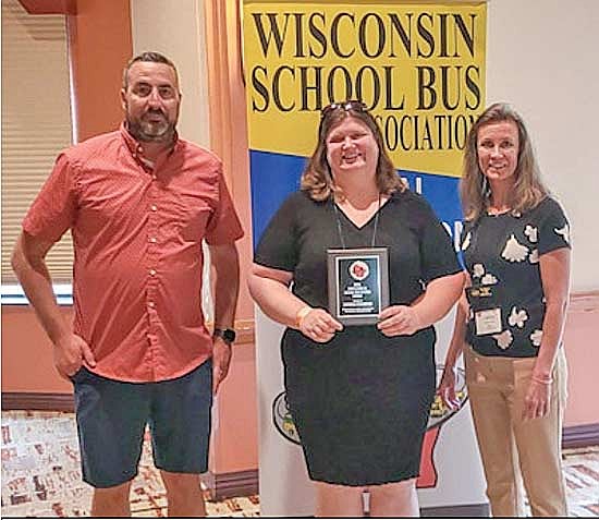 Wisconsin School Bus Association president Derrick Boxruker of Southwest Bus Service, left, and Wisconsin School Bus Association executive director Cherie Hime, right, present Patricia Townsend of Bowen’s Bus Service with an award recognizing exemplary service and professionalism. (Contributed photograph)
