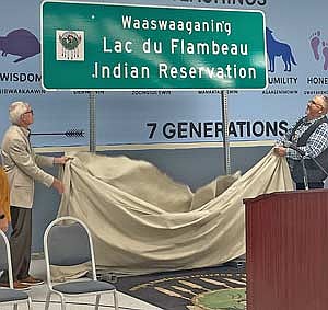 Wisconsin governor Tony Evers, left, and John Jonson, Sr., president of the Lac du Flambeau Band of Lake Superior Chippewa Indians, unveil a dual-language sign for Lac du Flambeau on Wednesday, July 23. (Photo by Brian Jopek/Lakeland Times)