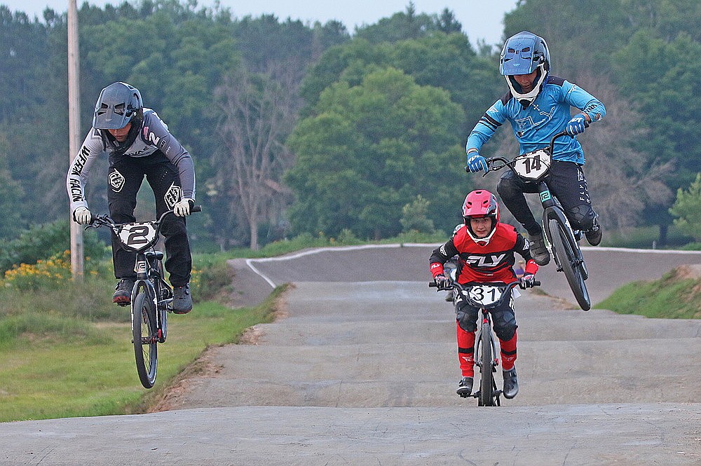 Jackson Wergin (2) of Hazelhurst and Alec Pilat (14) of Rhinelander catch air on a jump while Kaeden Bethel (31) of Tomahawk races behind in the 13 Expert class.