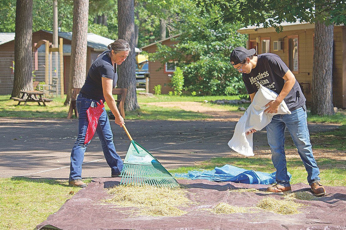 An Intertribal Manoomin/Manōmaeh “Wild Rice” Camp was held on Saturday, Aug. 30, at the North Lakeland Discovery Center in Manitowish Waters. Gretchen Gerrish, left, and Marshall Mitchell lay out harvested wild rice to dry in the sun. (Photo by Kate Reichl/Lakeland Times)