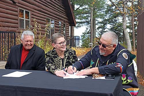Sister Sue Ernster, president of the Franciscan Sisters of Perpetual Adoration, signs over the ownership of the Marywood property in Arbor Vitae to the Lac du Flambeau Band of Lake Superior Chippewa Indians, represented by tribal president John Johnson, right, and business development corporation CEO Larry Turner, left. (Photo by Michael Strasburg/Lakeland Times)